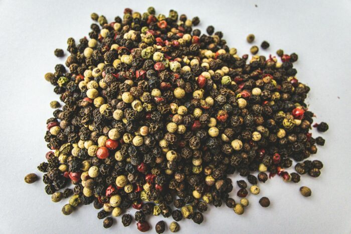 A close-up view of mixed peppercorns showcasing vivid colors on a white background.