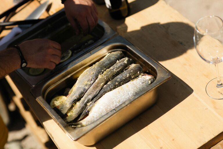 Fresh fish being seasoned and prepared outdoors for a delicious summer meal.