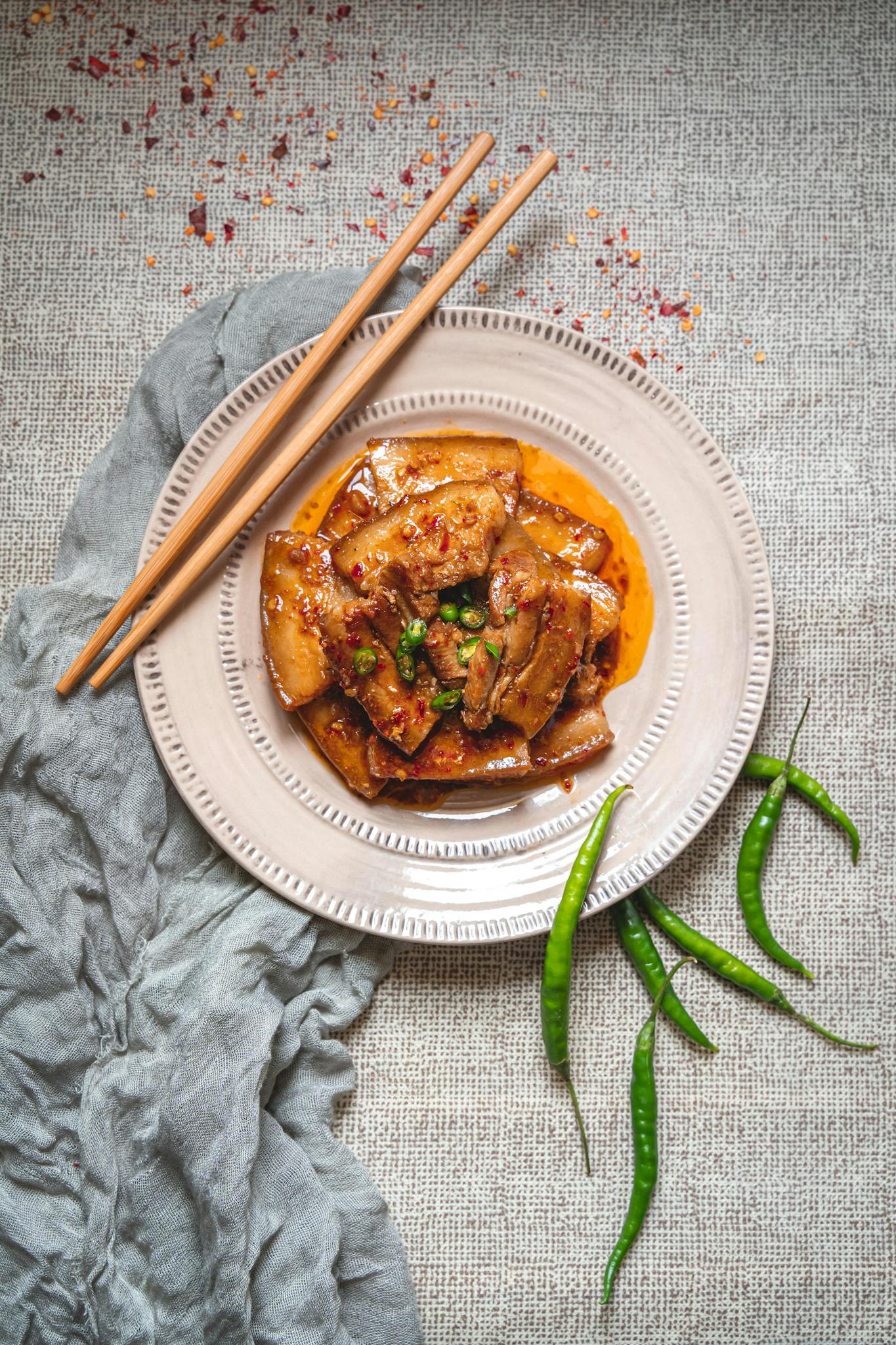 Top-down view of a spicy Asian dish with chili peppers on a ceramic plate. Perfect for food photography.